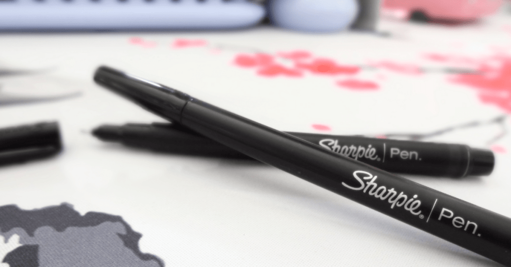 Close-up of black Sharpie Pens, one with its cap off showing off the fine point.