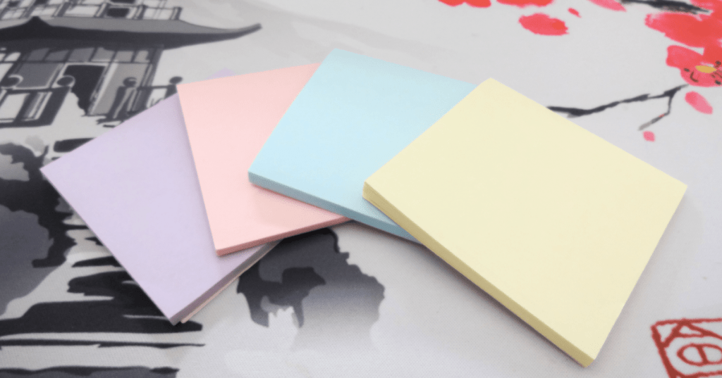 Four stacks of 3" x 3" Post-It notes in purple, pink, blue and yellow colors.