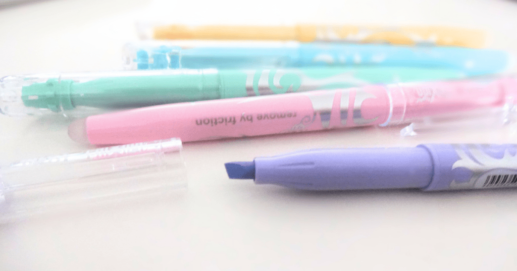 A variety of Pilot Frixion highlighters in pastel colors, one of them with its cap off and one has the writing "Remove by friction" on it.