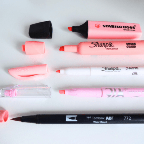 Pink highlighters from different brands placed in a row with their caps off.