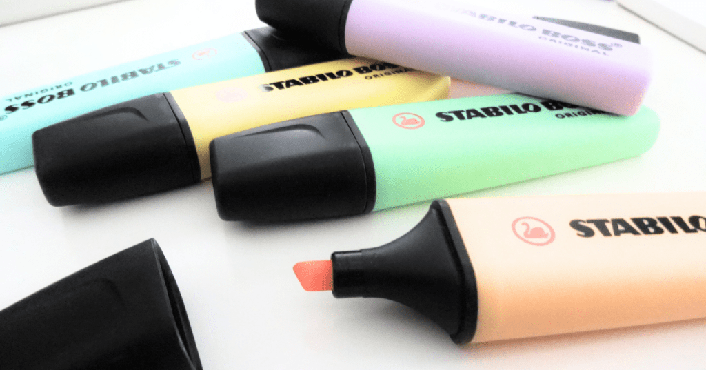 A variety of Stabilo Boss highlighters in pastel colors, one of them with its cap off.
