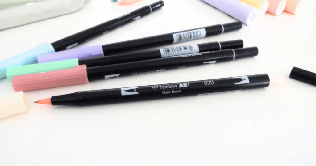A variety of Tombow Dual Brush Pen highlighters in pastel colors, one of them with both its caps off.