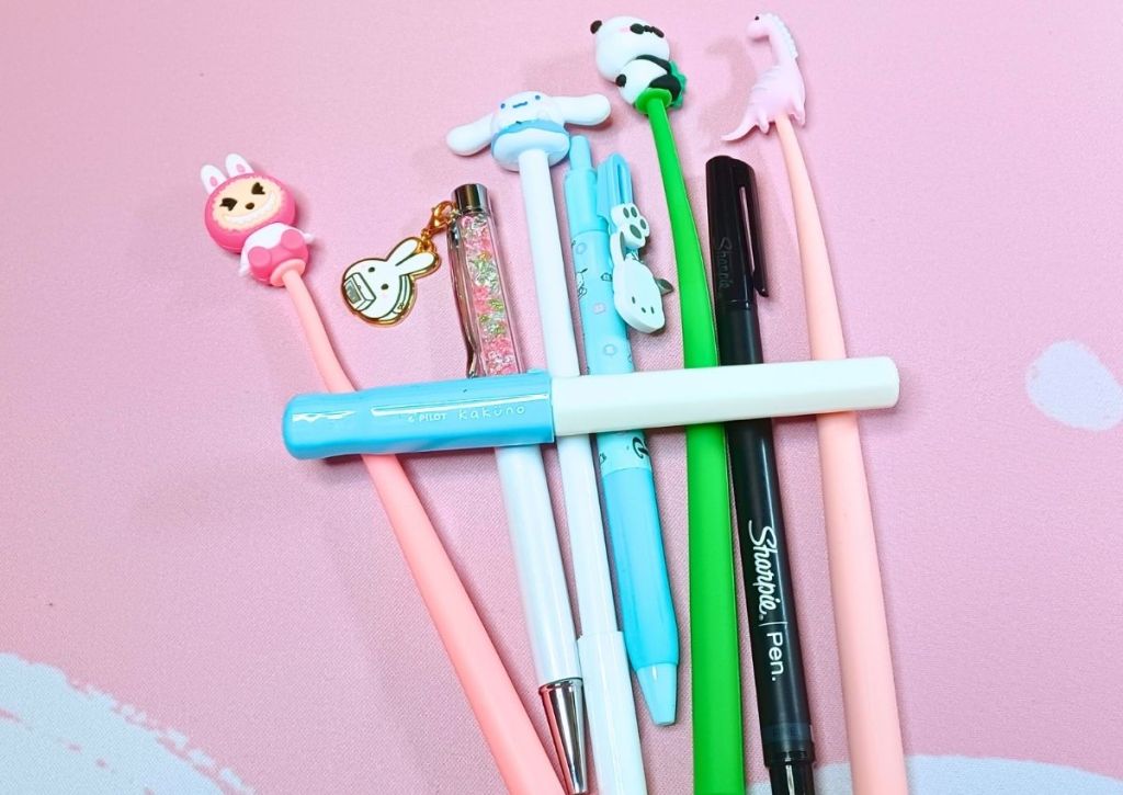 Cute and colorful pens placed in a row with a fountain pen placed across them.