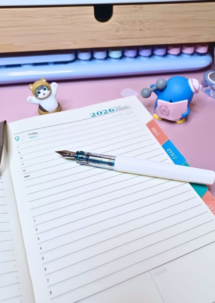 Open notebook on a blank daily page with the date printed in the corner and a fountain pen, uncapped, placed on the page.