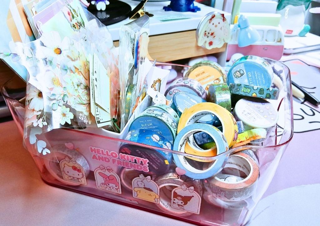 A small box overflowing with sticker sheets and rolls of washi tape