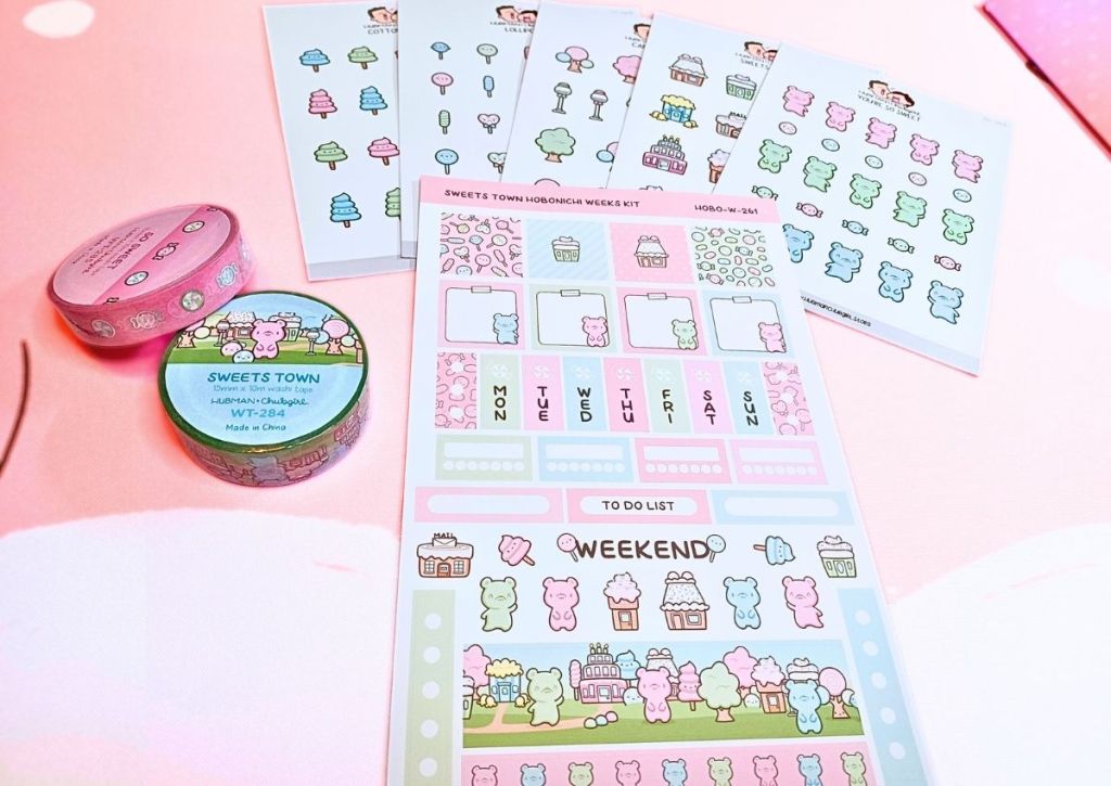 A flatlay of sticker sheets and washi tapes featuring a cute and colorful designs inspired by candies such as gummy bears and lollipop trees.