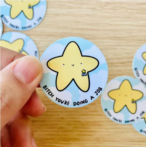 Round sticker featuring a smiling yellow star on the a blue background with the sentence "B*tch, you're doing a job."