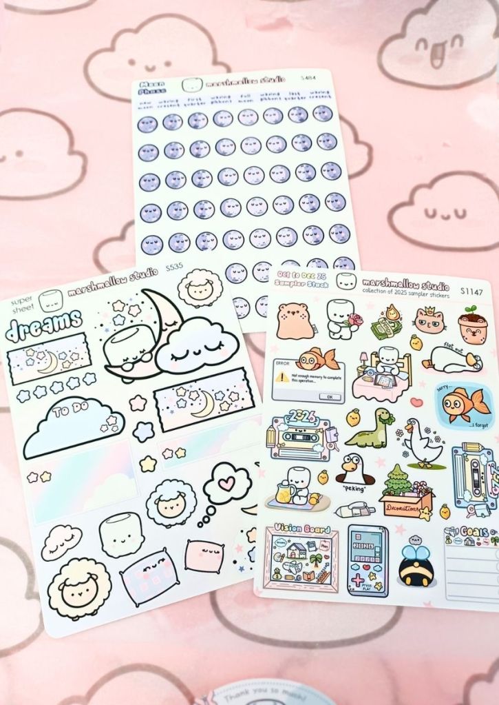 Three cute sticker sheets: one has a pastel dream design on it, one has purple moons following the moon phases, and one is a sampler with a variety of cute or funny designs.