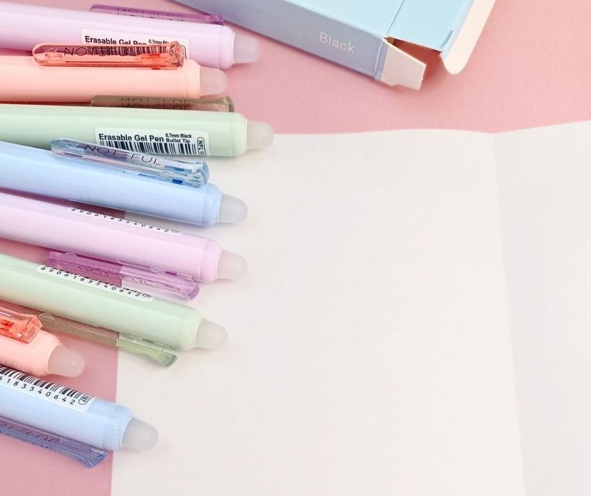 A pristine white sheet flanked by colorful pens on one side.