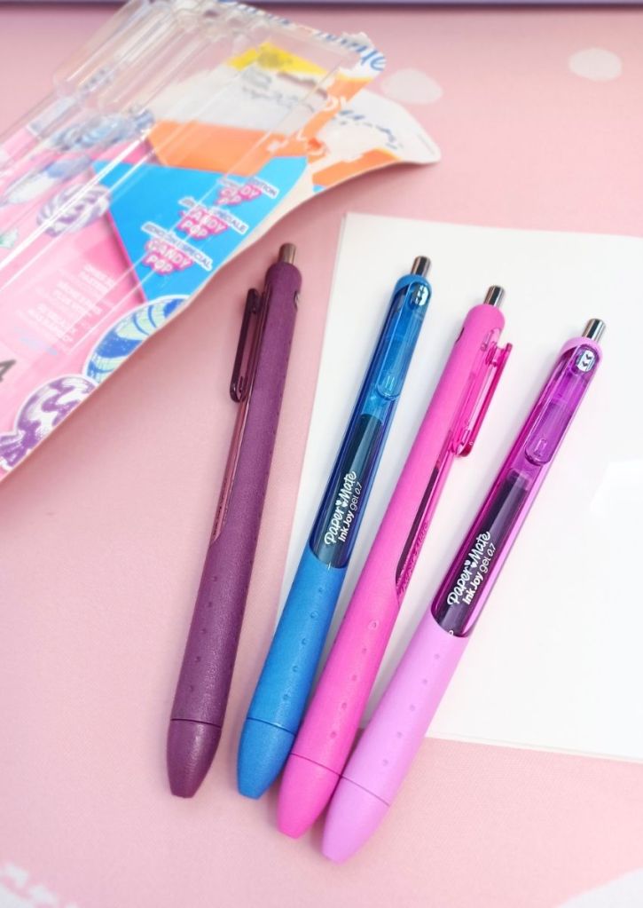 Four pens of purple and pink shades and one blue one.