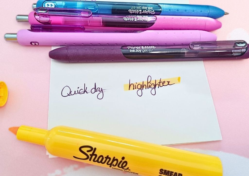 A white sheet surrounded by colorful pens and a yellow highlighter. On the sheet are a few lines, the words "quick dry" and the word "highlighter", the latter being highlighted in yellow.