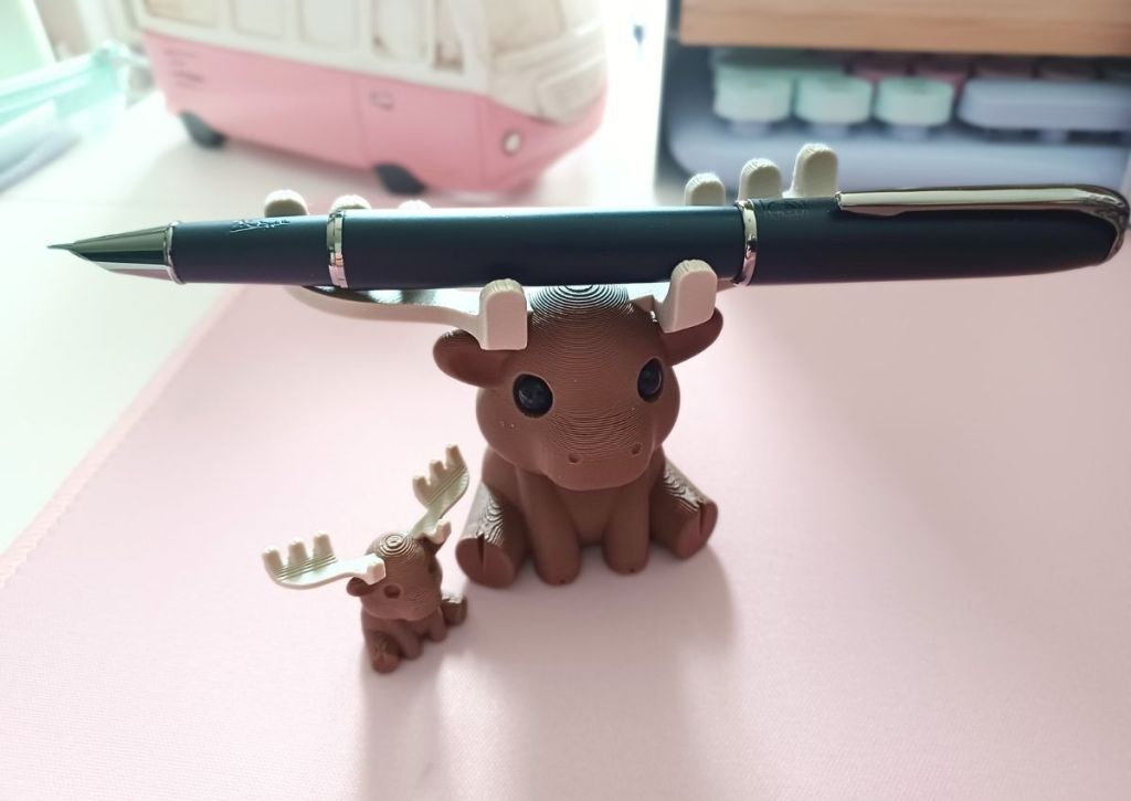 A cute moose pen-holder holding a fountain pen on his antlers.