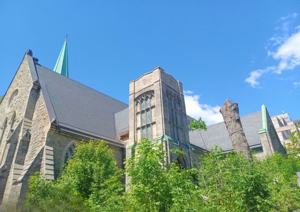 A church's imposing figure on a cloudless blue sky and surrounded by green foliage.