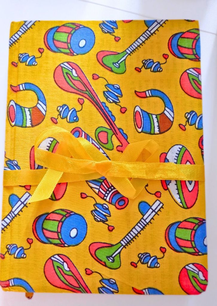 Yellow fabric cover featuring a colorful pattern of musical instruments tied with a yellow ribbon.
