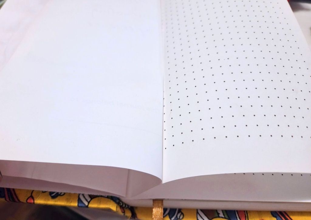 Open notebook with blank pages, one side featuring a dot grid pattern.