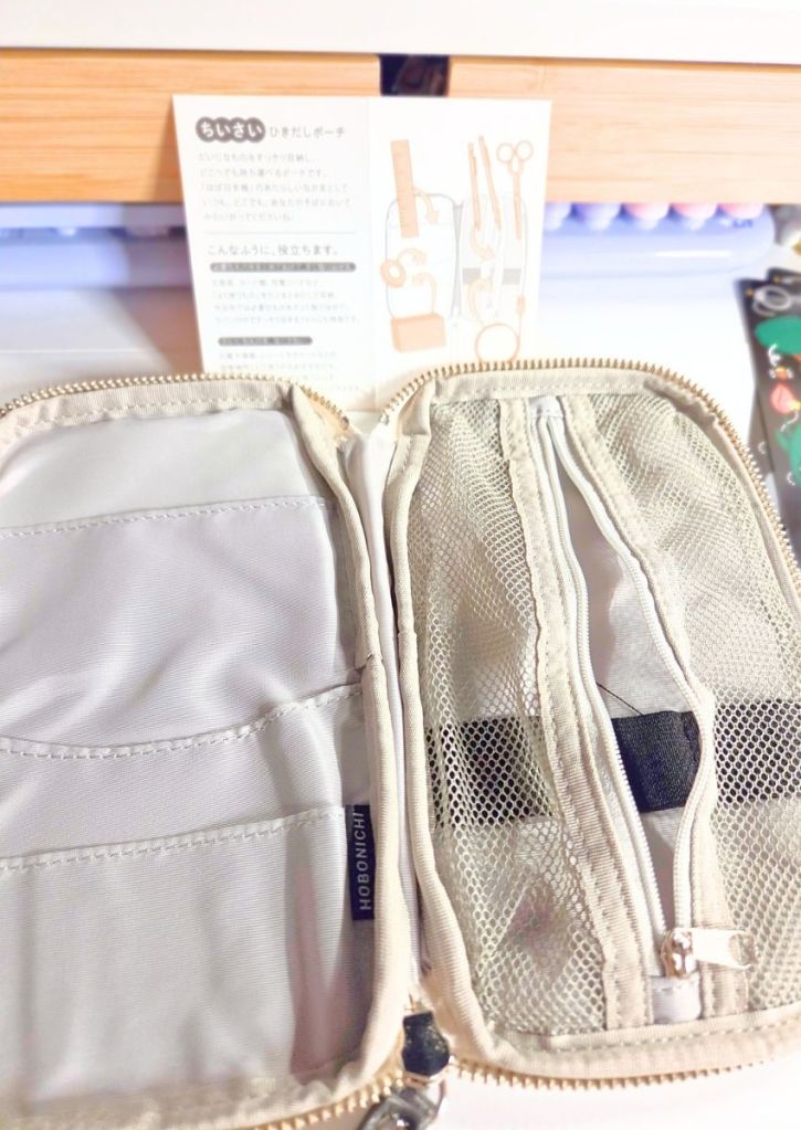 An open, beige zippered organizer pouch with multiple interior pockets and mesh compartments, shown with its instructional card.