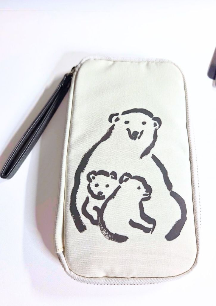 Off-white zippered pouch with a wrist strap, featuring a black line-drawing of a polar bear with two cubs.
