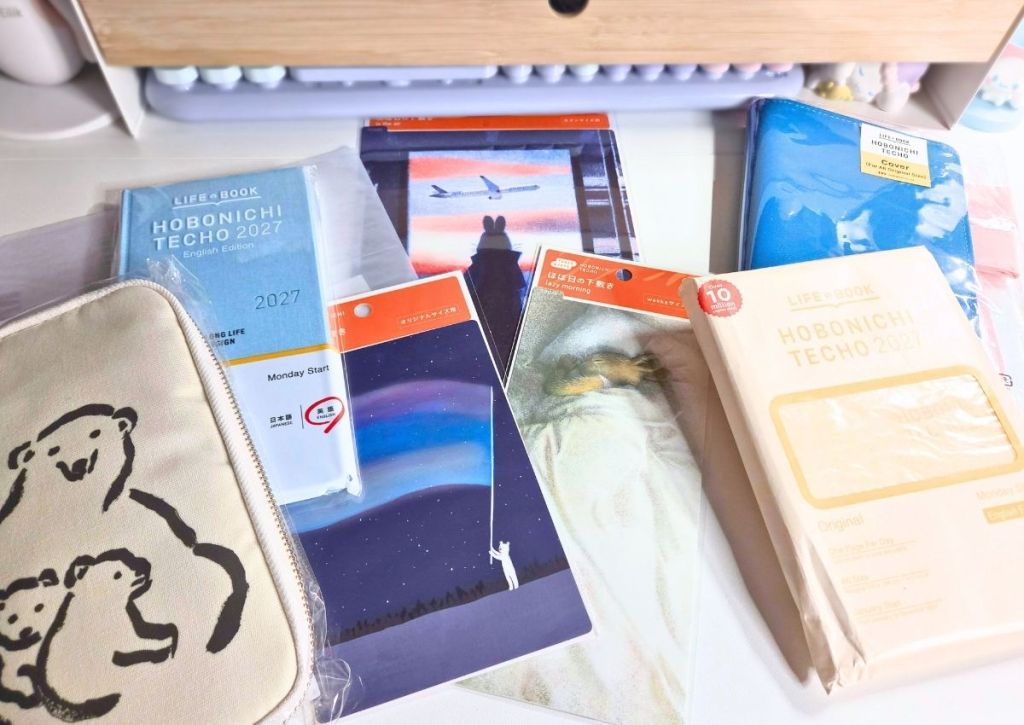 A collection of Hobonichi Techo 2027 planners, accessories, and a zippered case featuring a polar bear illustration.