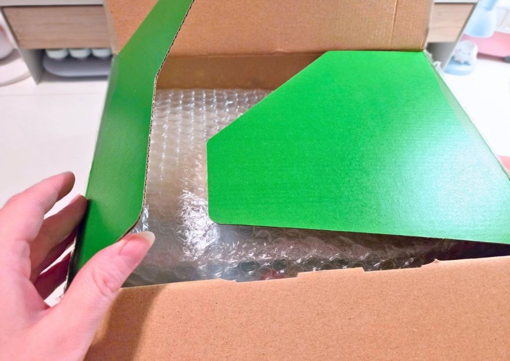 Hands opening a cardboard shipping box containing items wrapped in bubble wrap.