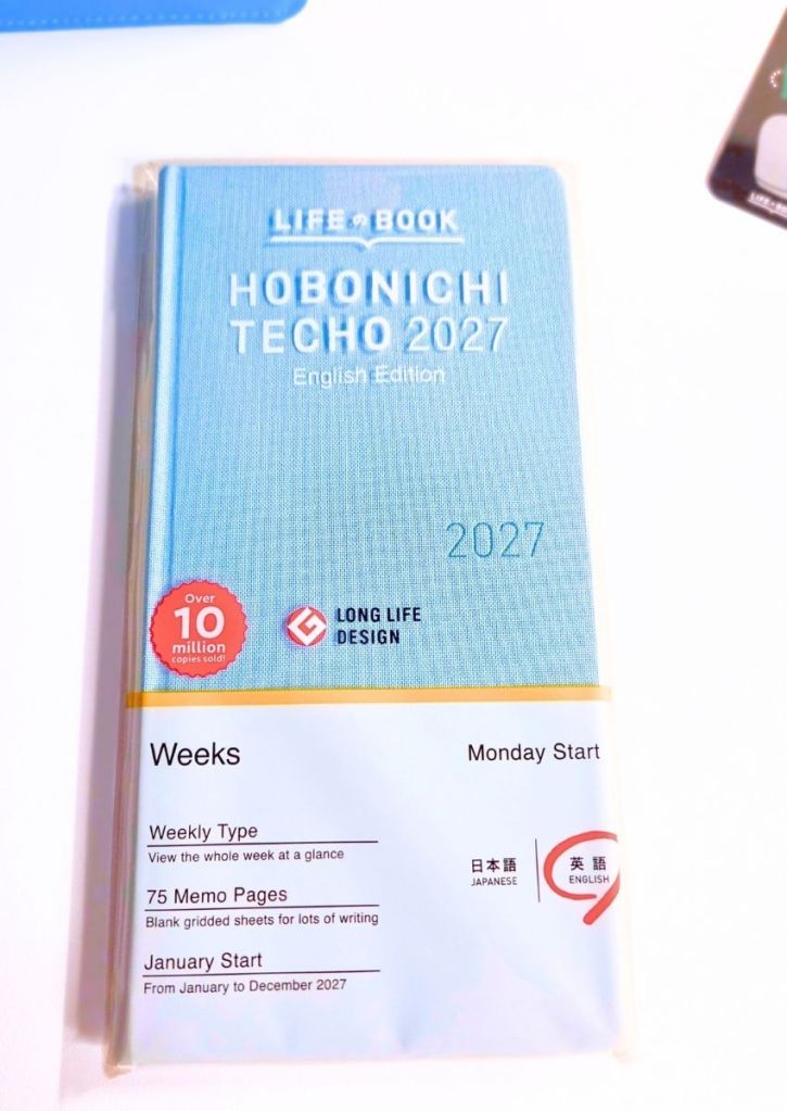 Light blue Hobonichi Techo 2027 Weeks planner in its clear plastic cover, featuring Monday Start, 75 memo pages, and a January start.
